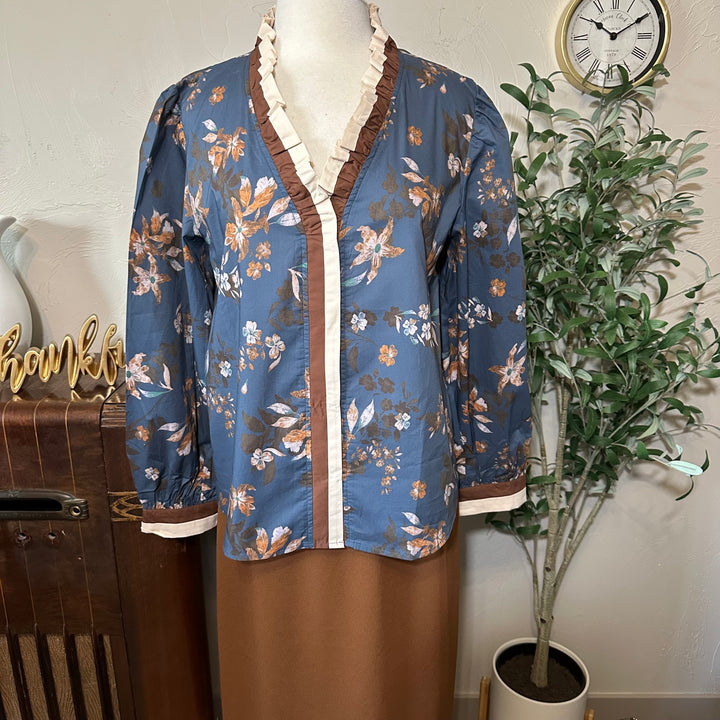 Front view of the dusty blue floral blouse with brown and cream trim down the button front