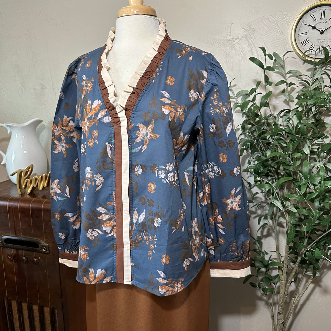 Angled close view of the ruffle collar, front trim and brown and cream cuffs
