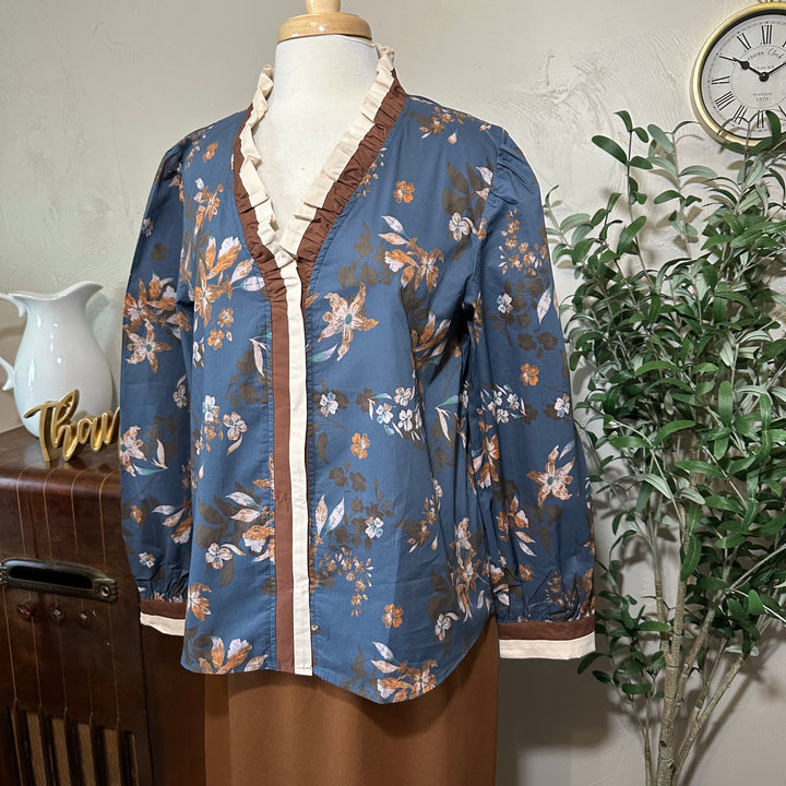 Angled close view of the ruffle collar, front trim and brown and cream cuffs
