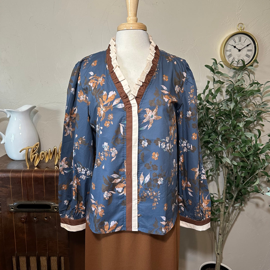 Closer front view of the floral blouse showing the ruffle collar and buttoned cuffs